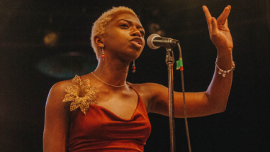 Woman in a red dress standing at a microphone.